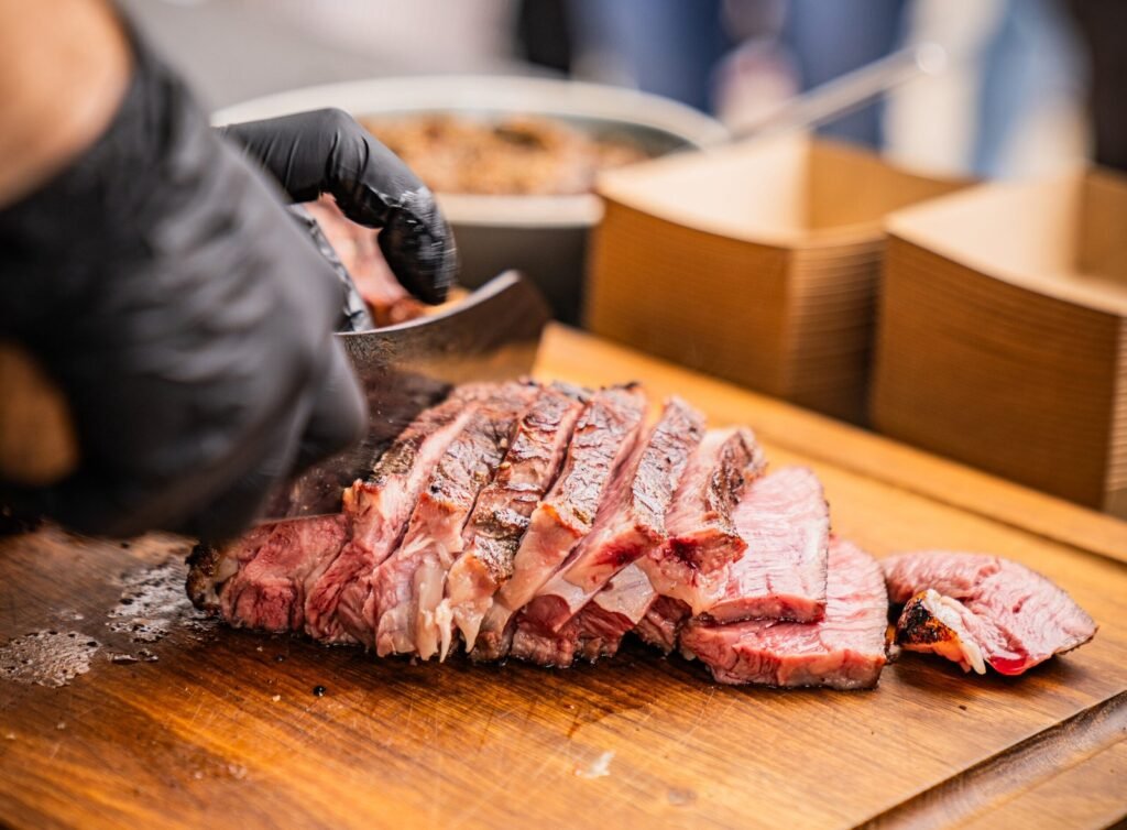 Frisch gegrilltes Steak wird auf einem Holzbrett in Scheiben geschnitten