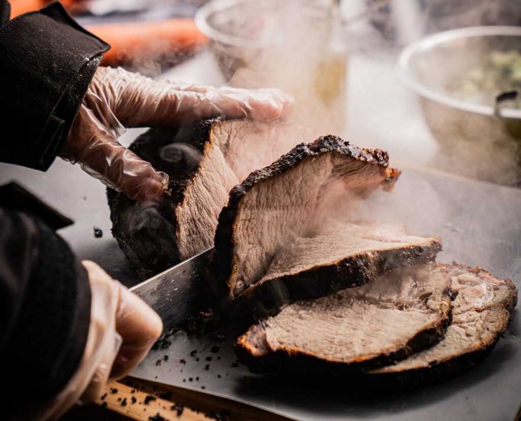 Frisch gegartes BBQ-Fleisch wird in dicke Scheiben geschnitten